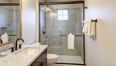 Walk-in shower with sliding glass doors and tiled walls